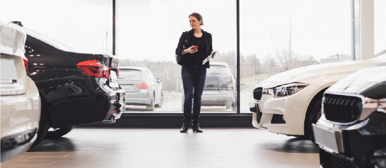 Person examining vehicles at a luxury car dealership.
